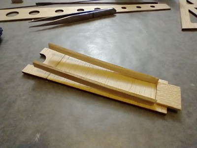 Battery hatch assembly. You can see the tongue that goes under the nose sheeting, the battery hatch glued to the scalloped piece for rubber band access, and the carefully glued on guides.